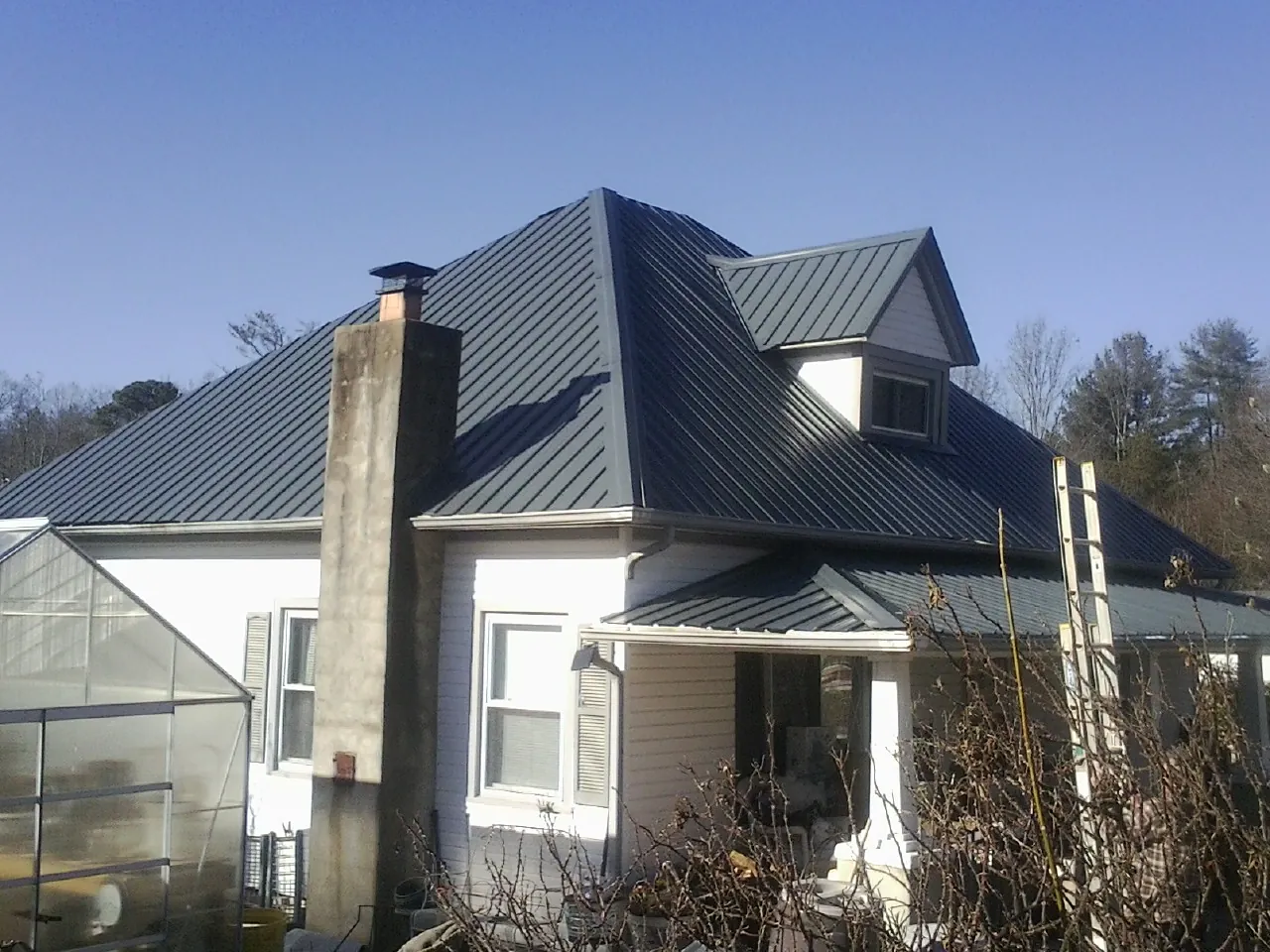 Dark blue standing seam metal roof on a white farmhouse with dormer — Slate & Tile Roof Repair by Roofing Brothers in Clarks Summit