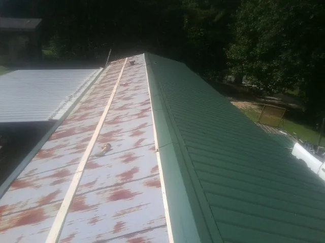 Old rusted panels beside newly installed green metal roofing — Wind Damage Roof Repair by Roofing Brothers in Clarks Summit