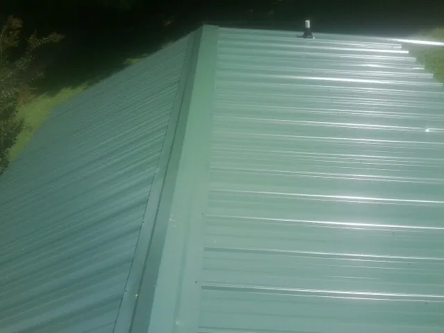 New green metal panels meeting at the ridge of a roof — Flat Roof Repair work by our crew in Clarks Summit