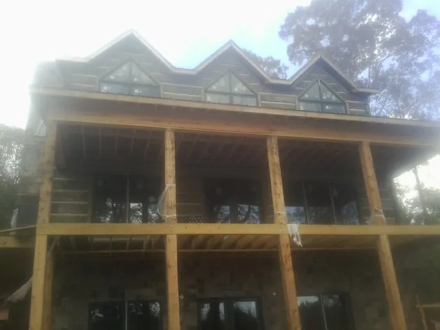 Dormers and porch framing on a large log home under construction — Roof Coating work by our crew in Clarks Summit