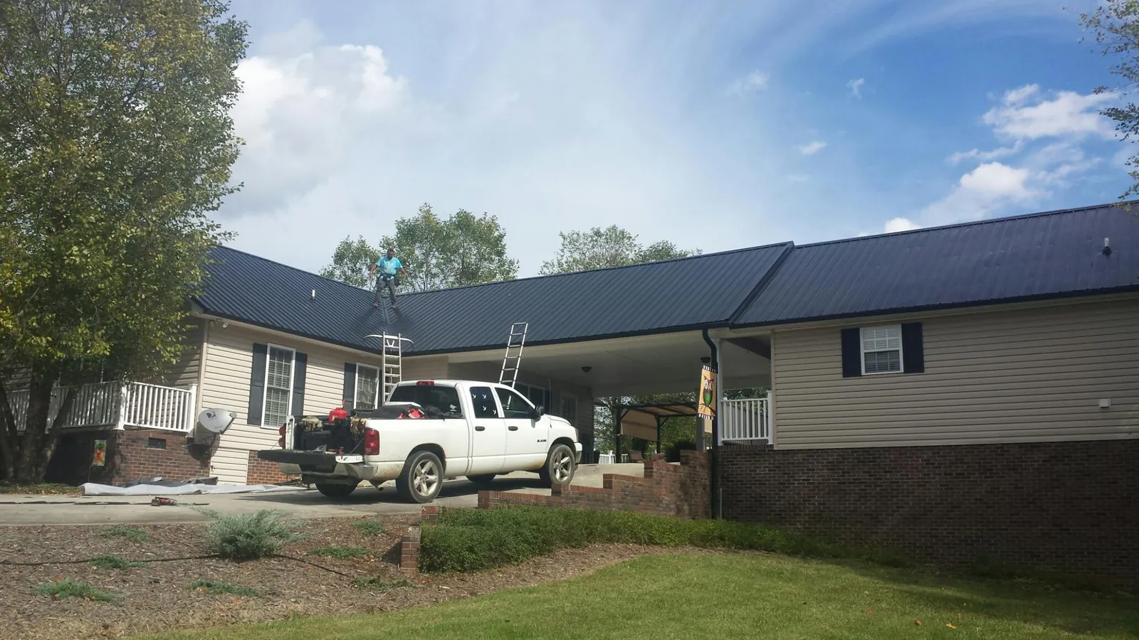 Black metal roof over a home and attached breezeway with ladders set in Clarks Summit