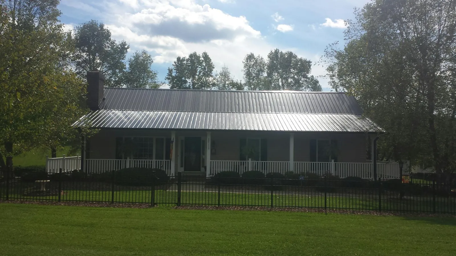 Gray metal roof on a brick ranch with a full width front porch — Gutter Guard Installation work by our crew in Clarks Summit