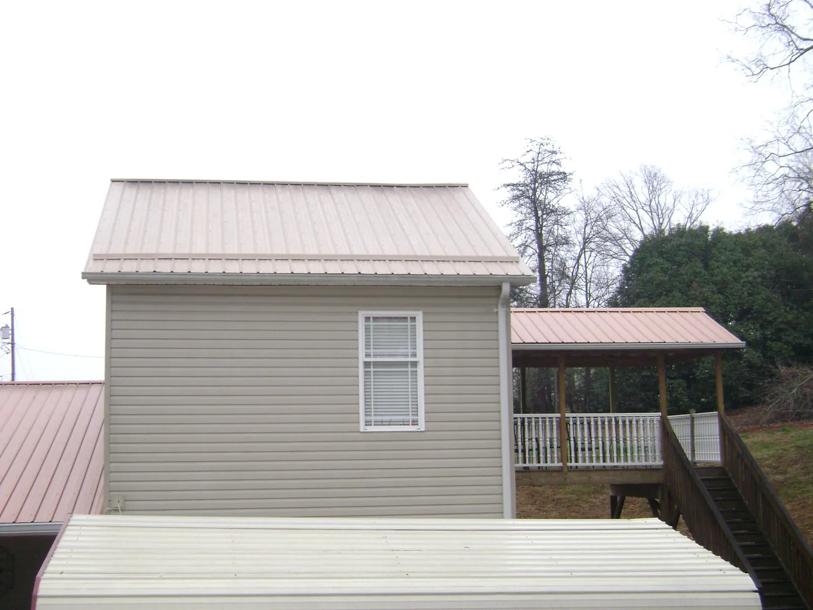Tan metal roofs on a two story addition and attached porch, from a Roof Replacement job in Clarks Summit