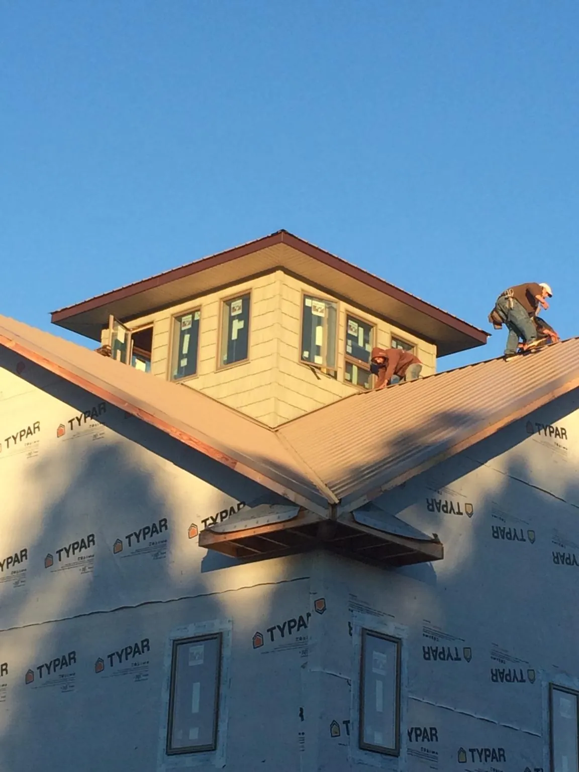 Roofers working around a rooftop cupola on a new metal roof at sunset — Roof Waterproofing in Clarks Summit by Roofing Brothers